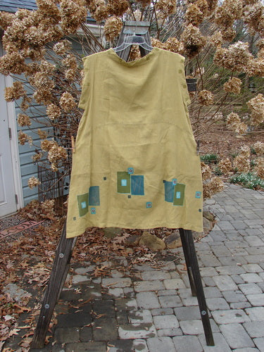 Barclay Linen Mid Layer Cap Sleeve Tunic in Mustard, a yellow dress with a varying widening hemline, downward curved front and rear drop empire waist seam, and a mock mandarin collar. Features continuous geometric theme paint. Size 2.