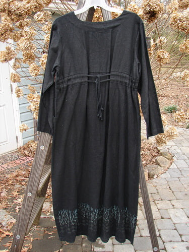 2000 Ringlet Dress Grass Row Black Size 1: A black dress with sectional panels, oversized pockets, and a V-shaped neckline. Made from weighted linen, it has a widening shape and a daisy-themed hem. Bust: 50, Waist: 50, Hips: 52, Length: 55 inches.