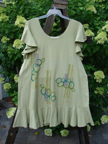 1996 Butterfly Dress Pebble Path Seedling Size 2: A light green dress with ruffled sleeves and a lower ruffled hem. Features a deep rounded neckline and a straight, elongating shape. Made from organic cotton with a pebble path theme paint. Bust 48, Waist 50, Hips 52, Flounce 80, Length 36.