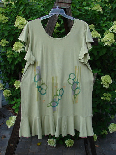 1996 Butterfly Dress Pebble Path Seedling Size 2: A light green dress with ruffled sleeves and a lower ruffled hem. The dress has a deep rounded neckline and a straight, elongating shape with a slight A-line flair. The dress features a pebble path theme paint design. Bust 48, Waist 50, Hips 52, Flounce 80, Length 36.
