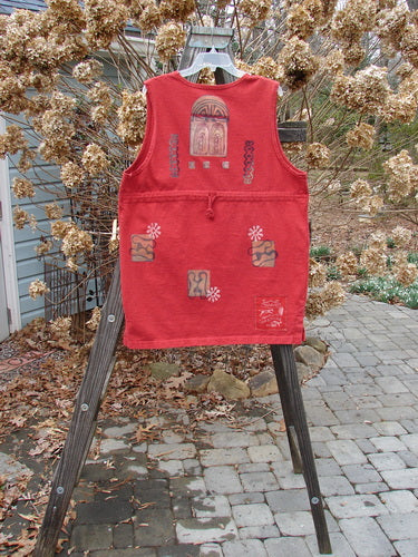 1996 Symbol Vest Gateway Pomegranate Size 1: A red vest with designs on it, made from heavy weight organic cotton. Vintage oversized button, knotted and textured chunky buttons, shallow neckline, not too deep arm openings, tiny vented sides, straighter shape, Blue Fish patch, rear drawcord. Bust 48, waist 48, hips 48, length 32 inches.