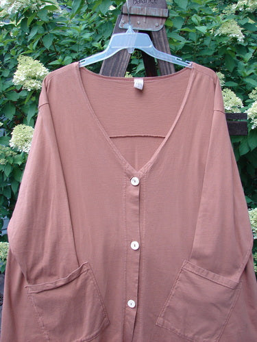 A Barclay Triangle Cardigan in Dusty Ochre, size 2, featuring a brown shirt with white buttons on a swinger. Funky front pockets set on an angle and a deep V-shaped neckline. Unpainted for easy coordination with other pieces.