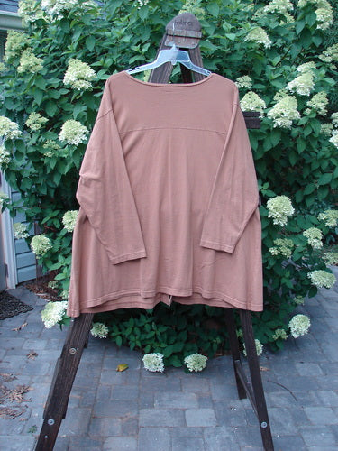 Image alt text: Barclay Triangle Cardigan in Dusty Ochre, size 2, on a swinger with white flowers on stone surface