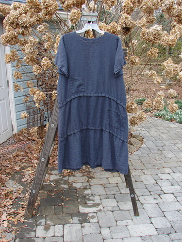 A medium weight linen dress in Blue Raven with a rounded neckline, straight shape, and versatile snap lengths. Features two front pockets and continuous horizontal snap tape. Barclay Linen Three Length Snap Dress Unpainted Blue Raven Size 1.