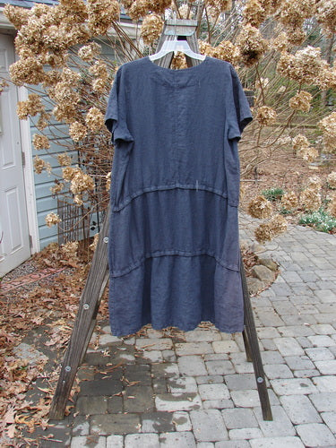 Barclay Linen Three Length Snap Dress Unpainted Blue Raven Size 1: A versatile blue dress on a wooden rack, featuring a rounded neckline, straight shape, and front pockets. Three continuous snap lengths allow for easy mixing and matching.