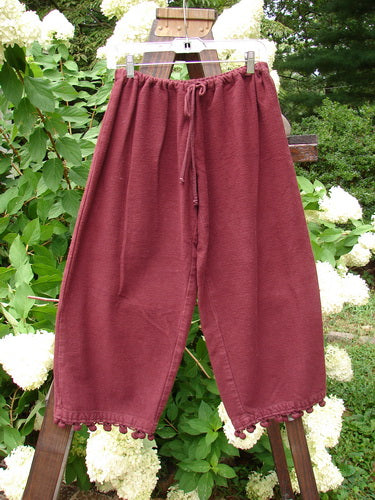 1999 Flannel PJ Pant Pom Pom Unpainted Wine Size 0: A pair of pants on a clothesline, made from heavy weight flannel. Crop length with pom poms around each cuff.