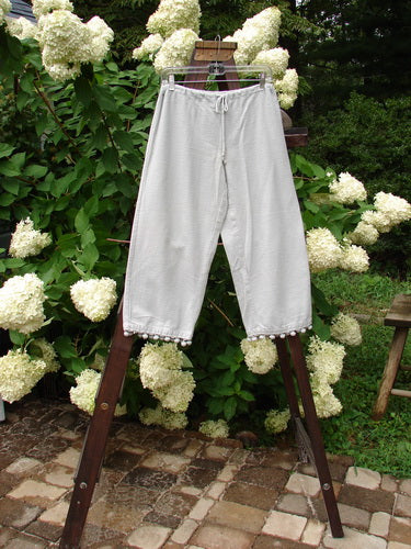1999 PJ Pant Pom Pom Unpainted Solstice Blue Size 0: Heavyweight flannel pants on a rack with pom poms on each cuff. Crop length, drawcord waist, and pocketless design.