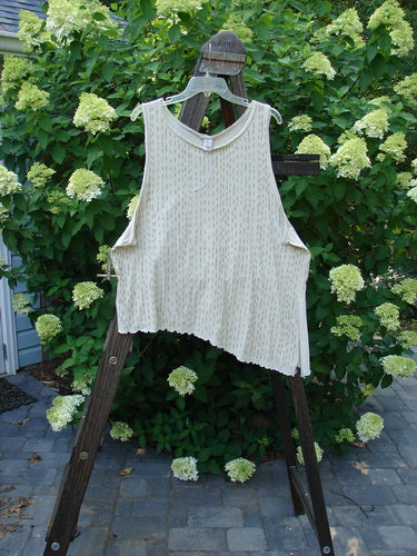 A Barclay Batiste Curly Seam Tank Rain Sand Size 2, a white shirt on a clothes rack, featuring all curly edgings, an asymmetrical lower vented hem, and deeper arm openings. Made from featherweight cotton batiste.