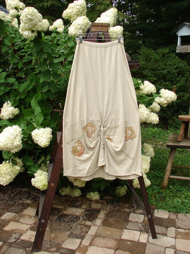 2000 Cotton Hemp Shade Skirt Bio Dove Size 1: A skirt on a rack, with a white dress featuring a flower design.