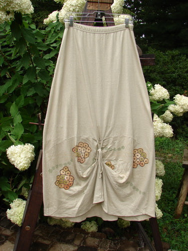 2000 Cotton Hemp Shade Skirt Bio Dove Size 1: A skirt on a rope, with a white dress featuring a flower design. A white flower in the shape of a heart adds a touch of elegance. The skirt is made from a lovely hemp cotton blend and has a full elastic waistband. The varying hemline can be adjusted with the extra long rippie. The skirt also features sectional horizontal panels and the classic resort biology theme paint. Perfect for a wedding or outdoor event.