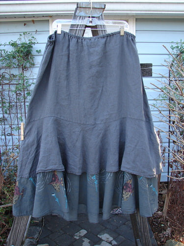 Barclay Linen Two Tier Ruffle Skirt Angel Fish Storm Grey Size 2: A skirt with a ruffle on a clothesline, featuring a wood pole and a tree branch.