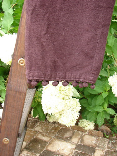1999 Flannel PJ Pant Pom Pom Unpainted Deep Burgundy Size 0: A close-up of a purple towel with a ladder and a white flower, representing the Winter Collection of 1999.