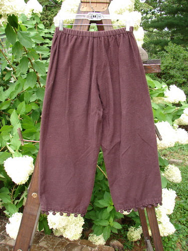 1999 Flannel PJ Pant Pom Pom Unpainted Deep Burgundy Size 0: A pair of pants with pom poms on the cuffs, made from heavy weight flannel. Crop length, draw cord front waistline, and elastic backing.