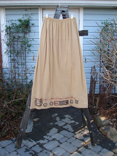 Image: A skirt on a rack with a close-up of a tree branch and a rock in the background.

Alt text: 1998 Scrabble Skirt Games Bamboo Size 2 - A beige skirt on a rack with nature elements.