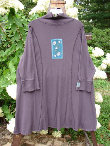 Barclay Patched Thermal Quad Drop Pocket Tunic Dress in Plum, Size 2. A long purple shirt with a blue patch on it. Features a double layered flop turtleneck, widening lower hem with four generous drop pockets, and a varying hemline. Made from cotton thermal.