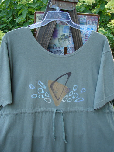 1996 Everyday Dress Step Stone Cricket Size 2: A grey shirt with a drawing on it, featuring a wide shape and a shallow neckline. Versatile and perfect for pairing with skirts or jeans.