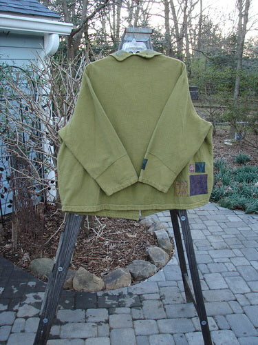 A green Barclay Patched Flannel Frolic Jacket on a swinger, featuring a ribbed corded outer, unique buttons, and a widening hemline. Size 2.