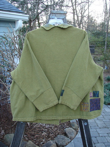 A green Barclay Patched Flannel Frolic Jacket on a swinger. Sweet roll over patched and painted neckline, contrasting lower sleeves, unique buttons, and a widening hemline. Cozy and swings just great! Size 2.