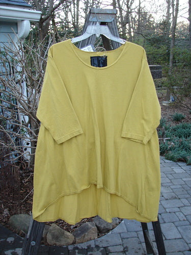 A yellow high low top with a swing silhouette on a clothes rack. Size 2, unpainted. Organic cotton.