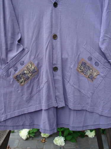 A close-up of a 1996 Triangle Cardigan in Purple Martin, featuring a deep V neckline, angled front pockets, and a garden bug theme paint.