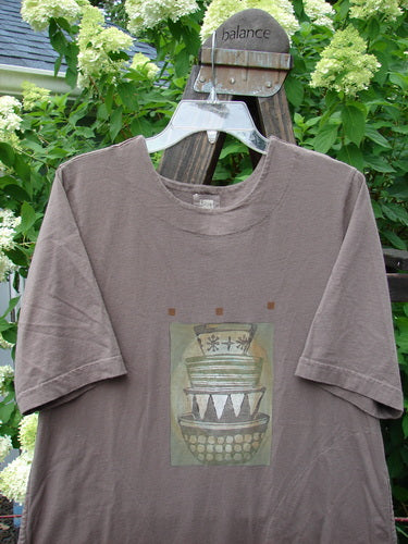 1999 Straight Dress Nesting Bowls Riverbed Size 1: a brown t-shirt with a picture of stacked bowls, featuring rounded side entry front pockets, a paneled neckline, widening hips, and a vented hemline.