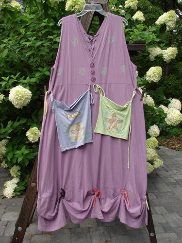 1997 Salt Water Taffy Jumper: Purple dress with bags on a wooden stand and clothesline. Features rippie accents, front and back pockets, textured buttons, and ocean-themed paint. Size 2, perfect condition.