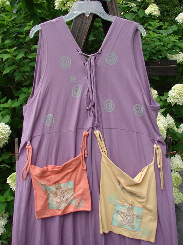 1997 Salt Water Taffy Jumper: a purple dress with a tie on the front, featuring rippie accents, front and back pockets, and ocean summer theme paint. Size 2.