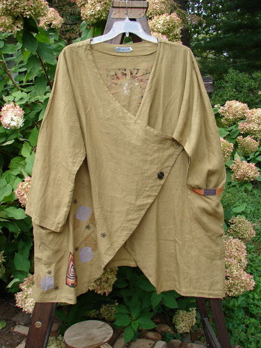 Barclay Cross Dye Linen Tidal Jacket Tree Swing Lentil Size 2: A long-sleeved shirt on a swinger, with a close-up of a jacket, fabric, bench, metal object, plant, and bush.