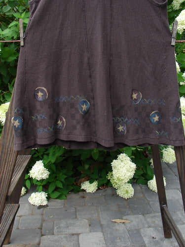 1999 Thermal A Line Vest Star Bounce Currant Size 1: A brown skirt on a clothesline, with a close-up of a chair and a bush in the background.