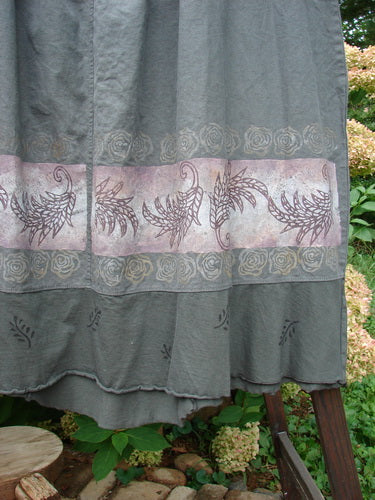 Barclay Linen Duet Skirt Green Raven Size 2: Grey fabric with pink design, close-up of curtain, wood surface, wooden railing, and plant.