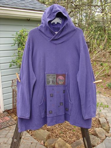 A cozy purple sweatshirt with a generous overlap front hoodie, front drop kangaroo pocket, and A-line vented lower. Made from heavy-weight organic cotton jersey fleece. Features a painted Tree of Life design.