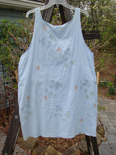 A white Barclay Batiste Slip Dress with a continuous tiny floral pattern, hanging on a clothesline.