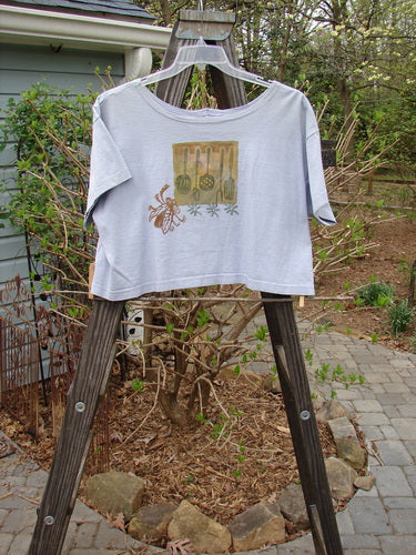 A lavender 1994 Song Top with a wide boxy shape, shallow neckline, and vintage kitchen garden theme. Features a front pocket and Blue Fish patch.