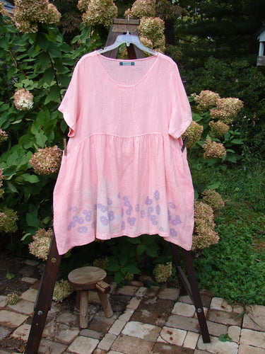 A Barclay Linen Studio Pullover Dress with a flouncy lower skirt and a daisy theme border. Size 2 in peach.