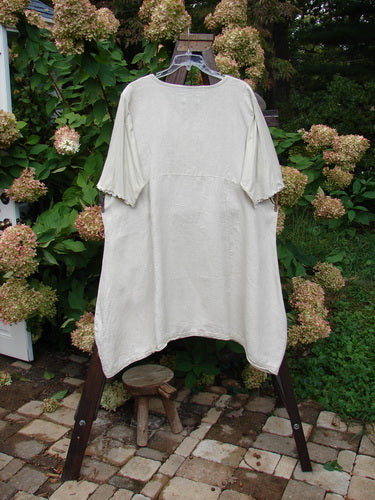 Barclay Linen Lace Blooming Tunic Dress Unpainted Wheat Size 2: A white shirt on a swinger with a small wooden stool and a plant.