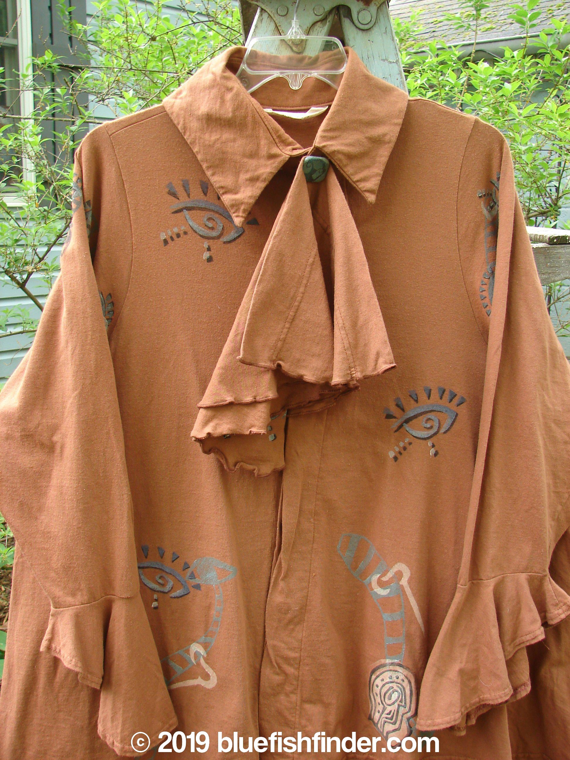 1996 Flutter Jacket Abstract Cassia Size 2: Brown jacket with a large bow, hidden button front, and triangular removable flounce. Features flutter sleeves, ruffled rear hemline, and generous hip measurements. Made from organic cotton.
