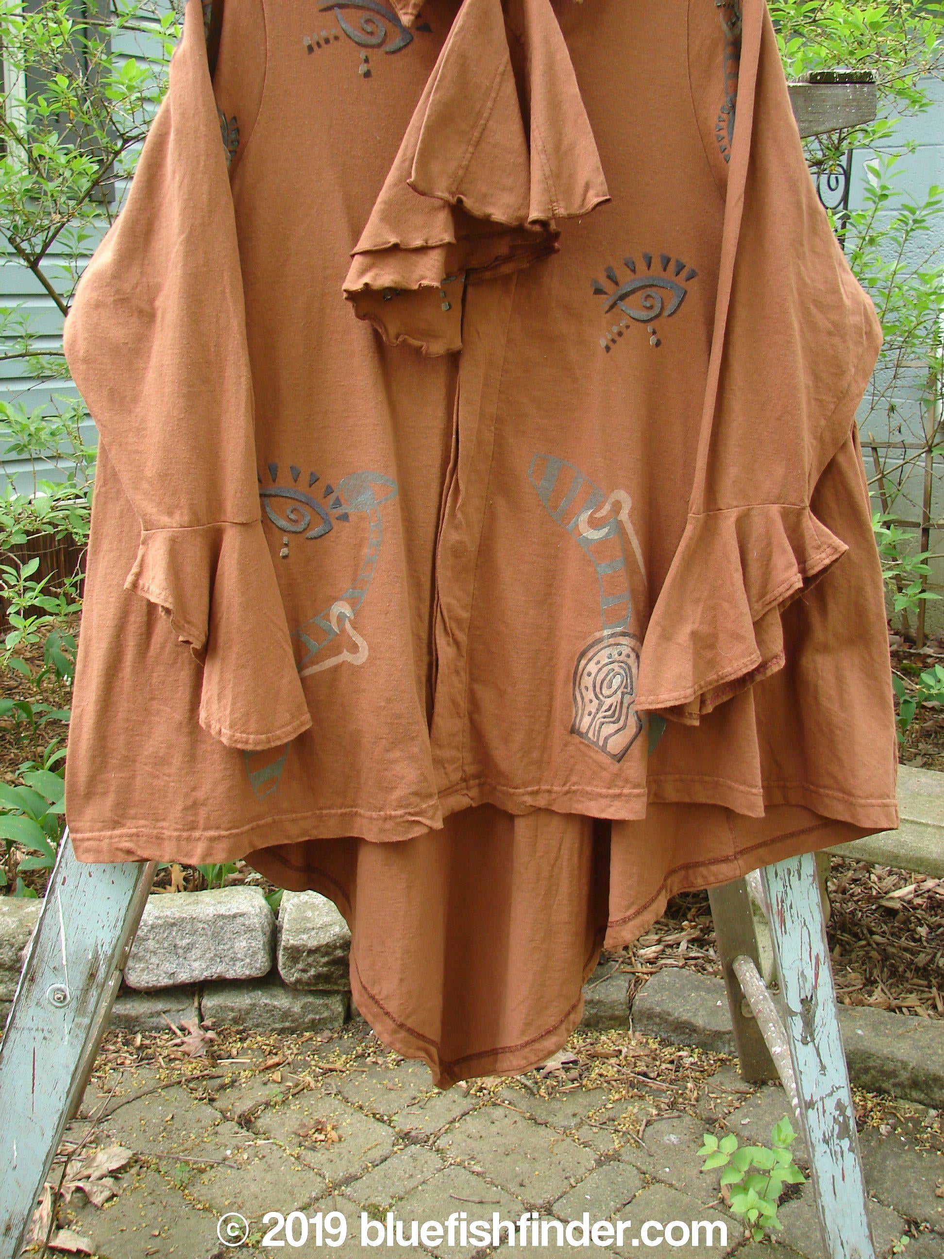 1996 Flutter Jacket Abstract Cassia Size 2: A brown shirt with a unique design. Hidden button front with a painted cloth covered button. Triangular removable flounce on front and back. Dramatic ruffled rear hemline. Flutter sleeves. Wild abstract theme paint. Generous hip measurements.