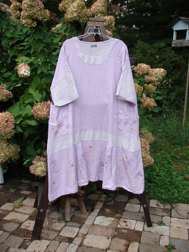 Barclay Linen Contrast Drop Pocket Dress Tiny Flower Heathered Lilac Size 2: A dress on a rack with a widening shape, flutter flounce, and front seams.