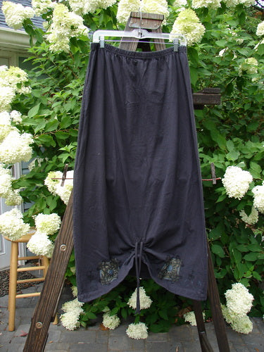 1999 Winter Skirt Celtic Five Raven Size 2: A black skirt on a clothesline with a lower peg shape, featuring a scooped front hemline and a full elastic waistline.
