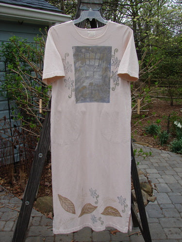 A white shirt with a painted design on it, featuring a square design, leaves on a white towel, and a close-up of a wooden post.