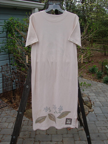 A white shirt on a clothes rack, part of the 1999 Straight Dress Window Chair Teadye Size 0 collection. Made from organic cotton, it features rounded side entry front pockets, a paneled neckline, widening hips, and a narrowing vented hemline. The dress is in perfect condition and includes the signature Blue Fish Patch.