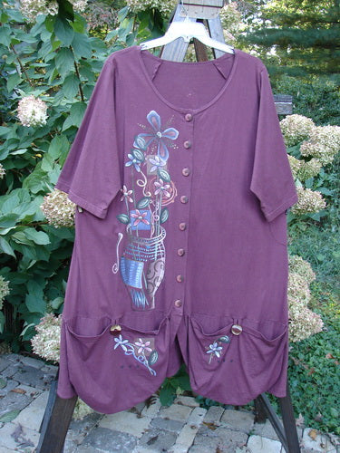 Barclay Short Penny Dress Garden Show Red Plum Size 2: A purple dress with a painting of a garden show theme. Features a rounded neckline, widening shape, and painted pockets.