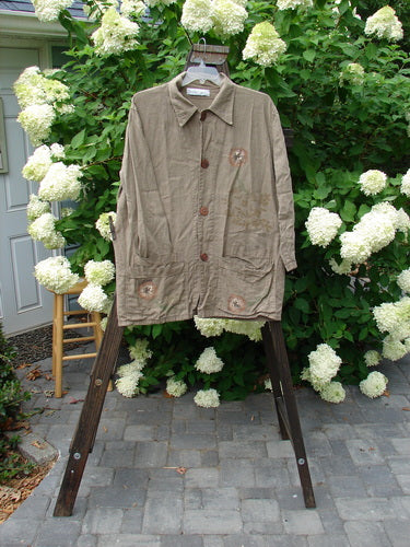 1998 Botanicals Herbary Jacket: Heavy Weight Linen coat on a rack. Features include ceramic buttons, painted pockets, and a botanical theme.