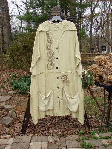 Image alt text: "Barclay Silk Linen Collar Coat Wind Star Plantain Size 2 - A long dress with a prominent pointed collar, exterior stitchery, and sectional panels. Features a varying vented hemline, unique super swirl buttons, and silk contrasting drop hem pockets."