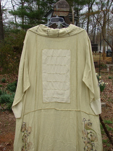 A white linen and silk coat with a prominent pointed collar, unique super swirl buttons, and contrasting silk and linen fabrics. Features exterior stitchery, sectional panels, and pinched drop hem pockets. Size 2.