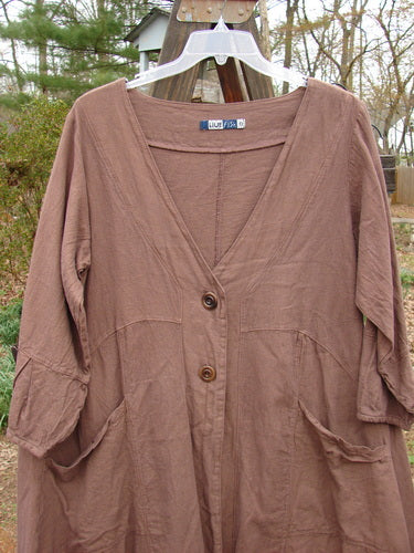 Image alt text: "Barclay Linen Adras Uptown Jacket on clothes rack, featuring deep V neckline, pleated lower sleeves and hemline, double drop front pockets, and varying hemline. Size 0, unpainted Redwood color."