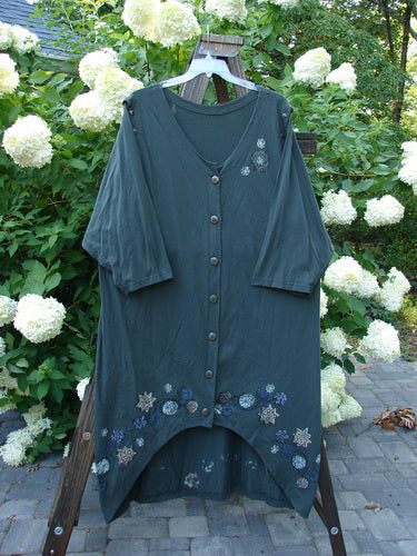 Image alt text: "1994 Convertible Coat with Spin Flower design, Deep Moss color, OSFA. Versatile coat with button-on/off sleeves, duster look, and unique front hemline. Texture and contrast make a statement. Bust 44, Waist 54, Hips 56, Front Length 38, Back Length 50, Hem Circumference 72 inches."