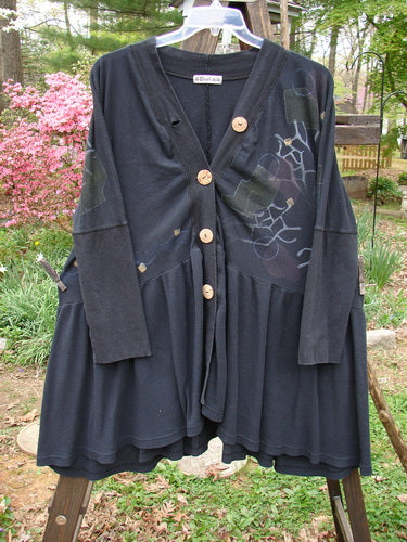Barclay Thermal Bungalow Jacket: A black dress with buttons on a clothes rack. Deep V-shaped neckline, giant wooden buttons, and a sweeping gathered flounce. Empire waist seam, upward scooped front varying hemline. Super stretch and thicker lower sleeves. Abstract modern graphics theme paint.