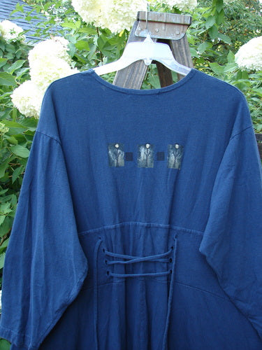 1997 Caryatid Dress Quad Art Window Pane Size 2: A vintage blue shirt with a patch on it. Features adjustable laces and a wide A-line lower for versatile sizing. Made from mid-weight organic cotton.