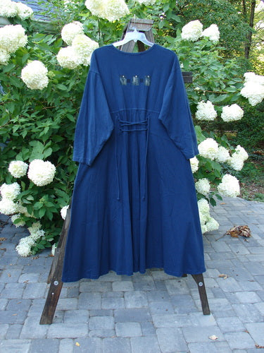 1997 Caryatid Dress Quad Art Window Pane Size 2: A vintage blue dress on a rack, made from mid-weight organic cotton. Features adjustable laces in front and back for versatile sizing. Drop shoulders, sweeping A-line lower, and quad art theme paint. Bust 52-60, waist 52-60, hips 62-70, hem circumference 140, length 56 inches.